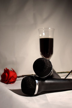 Karaoke set on a white background .. Microphones, glass of wine and red rose