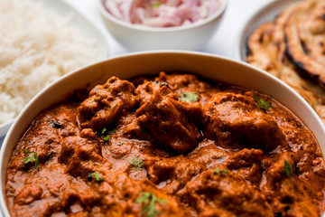 Murgh Makhani / Butter chicken tikka masala served with roti / Paratha and plain rice along with onion salad. selective focus