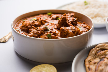 Murgh Makhani / Butter chicken tikka masala served with roti / Paratha and plain rice along with onion salad. selective focus