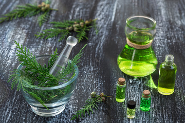 mortar and Juniperus communis twigs,Bottle of cypress tincture, infusion, oil on grey wooden...