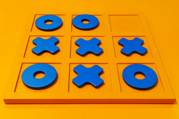 board game tic-tac-toe, blue figures on a bright orange field, match result - the crosses won