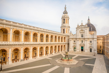Square of Loreto, Basilica della Santa Casa in sunny day, portico to the side, people in the square in Loreto, Ancona in Italy
