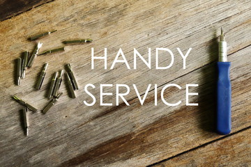 Handy service written on wooden background with screwdriver.