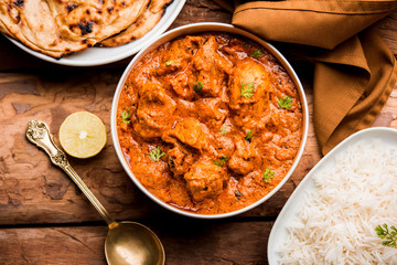 Murgh Makhani / Butter chicken tikka masala served with roti / Paratha and plain rice along with onion salad. selective focus