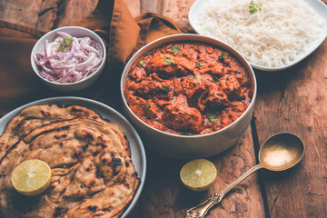 Murgh Makhani / Butter chicken tikka masala served with roti / Paratha and plain rice along with onion salad. selective focus