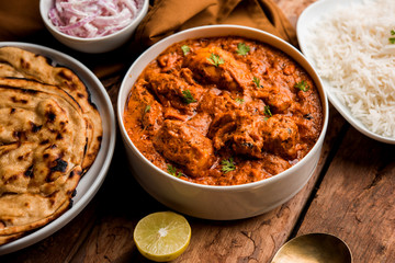 Murgh Makhani / Butter chicken tikka masala served with roti / Paratha and plain rice along with onion salad. selective focus