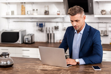 Fototapeta premium handsome businessman in formal wear using laptop at home