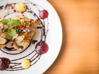 Danish pastry with syrup and sprinkle with almonds and chocolate balls. Put on a white plate with jam around.