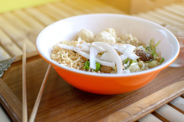 Noodles in an orange bowl placed on a table.