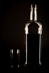 Silhouette of a bottle of alcohol with a glass on a black background - obrazy, fototapety, plakaty