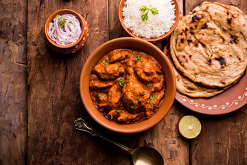 Murgh Makhani / Butter chicken tikka masala served with roti / Paratha and plain rice along with onion salad. selective focus