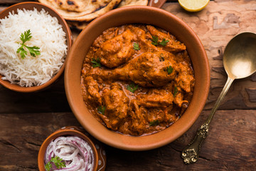 Murgh Makhani / Butter chicken tikka masala served with roti / Paratha and plain rice along with onion salad. selective focus