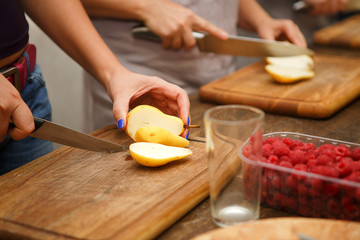 Woman in the kitchen cuts a pear. Processing fruits with tools. Slicing pear. Healthy food. Dessert without sugar