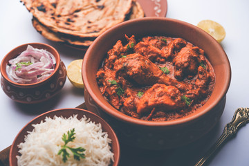Murgh Makhani / Butter chicken tikka masala served with roti / Paratha and plain rice along with onion salad. selective focus