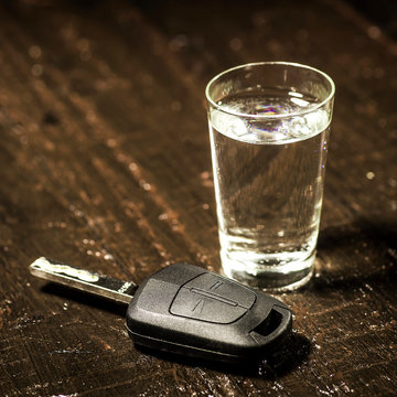 The concept of driving under the influence of alcohol - car keys, a glass of alcohol