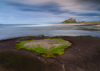 Bamburgh Castle on the Northumberland Coast, England, under evening sunshine.