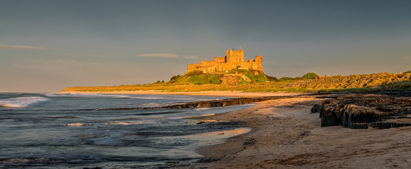 Bamburgh Castle on the Northumberland Coast, England, under evening sunshine.