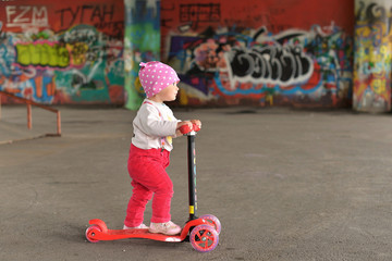 A little girl riding a scooter in a skate Park.