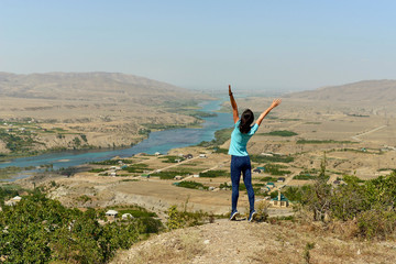 Sulak river in Dagestan and the village along the river. The woman is happy in this beautiful place.