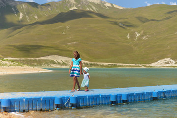 Beautiful mountain blue lake in the Chechen Republic. Sister girls walking on the pier.
