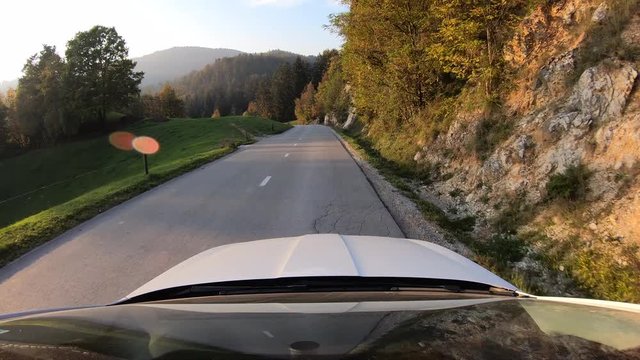 Car driving on a road in the countryside in sunshine flares.