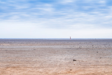 Fototapeta na wymiar lonely man walking on the beach alone on the coastline shore under a blue nice sky. travel amnd enjoy the outdoors spaces concept to feel the nature and the energy of Earth