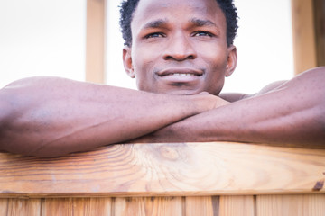 Beautiful black afro race ethnic male smile and relax on a wood bar. close up portrait of young millennial people enjoy the life and the age. Beautiness and model concept