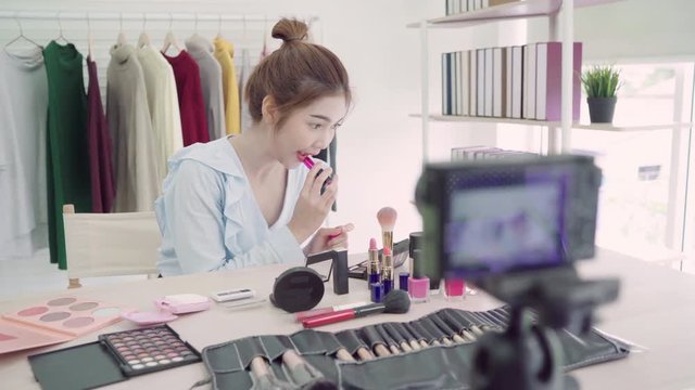 Beauty blogger present beauty cosmetics sitting in front camera for recording video. Beautiful asian woman use cosmetics while review make up tutorial broadcast live video.