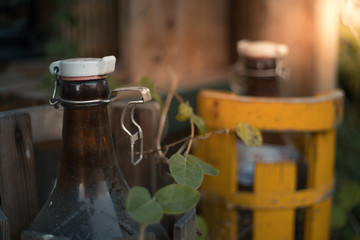 Two big brown glass bottles in wooden containers an autumn evening 