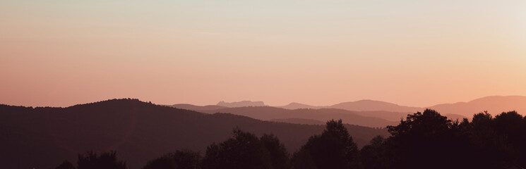 Dark tones of panoramic range mountains at sunset.