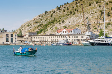 Fototapeta na wymiar Pleasure boat in the sea bay. Russia, Republic of Crimea, Balaclava. 11.06.2018: Pleasure boat with tourists in Balaklava Bay