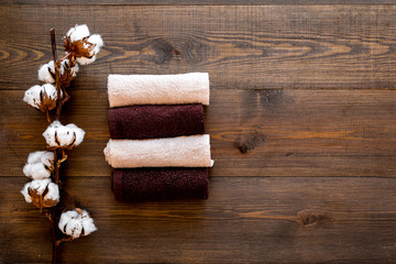 Fototapeta premium Cotton towels high quality. Set of towels twisted coil near dry cotton flowers on dark wooden background top view copy space