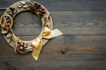 Creative, unusual christmas wreath made of thread, dry fruits and nuts on dark wooden background top view space for text