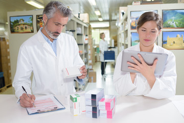 Obraz premium pharmacists holding tablet in hands while doing inventory