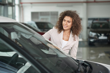Female customer of car dealership choosing automobile.