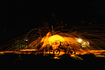 Burning steel wool spinned in the forest. Showers of glowing sparks from spinning steel wool