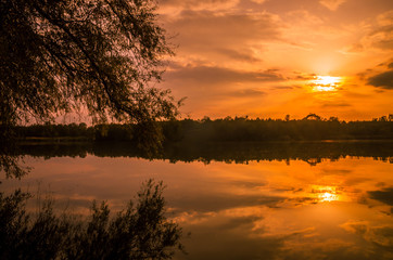Fototapeta na wymiar Sunset over a river delta in fall. Autumn evening landscape with a lake surrounded by reeds and straw