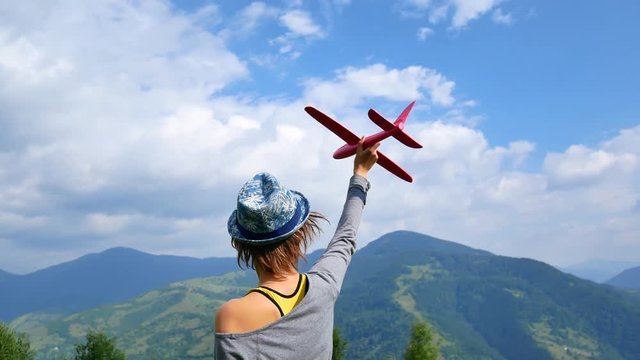 Young pretty woman back to the camera and keeps the red model of the plane in ruach. concept of travel and freedom.
