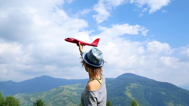 Young pretty woman back to the camera and keeps the red model of the plane in ruach. concept of travel and freedom.
