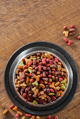 Dry Colorful cat food in metal bowl on wooden background