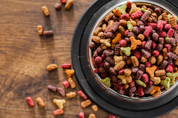 Dry Colorful cat food in metal bowl on wooden background