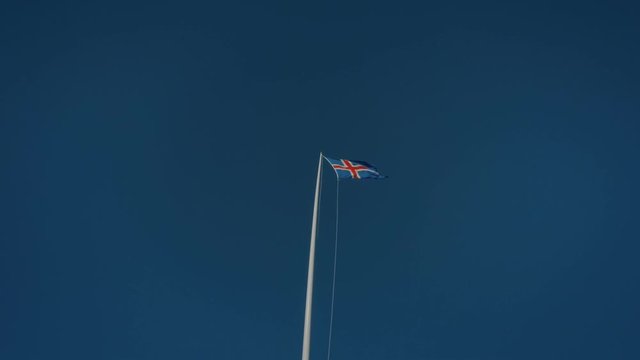 Simple and clean shot of bright blue sky with icelandic flag hanging on pole, proud and free, flapping in wind on independence day. Iceland new travel destination for nature lovers