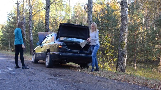 Two beautiful girls, the car broke down on the road, autumn
