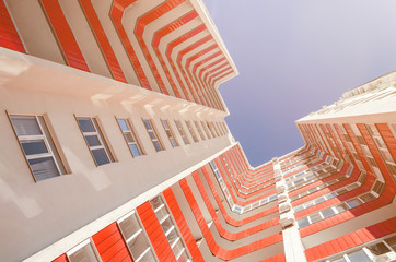 View of a residential building from the bottom up. White house with red balconies in a warm sunny day