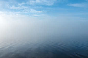 Soft ripples in misty pastel landscape. Peaceful thick fog on lake. Beautiful background.