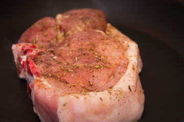 Fresh raw pork steak with spices roasting on frying pan