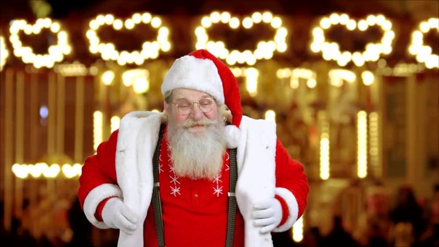 Santa Claus on New Year lights background. Cheerful authentic Santa Claus is dancing on festive background. The holiday is coming.