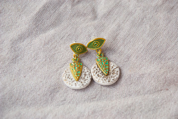 Egyptian bohemian earrings gold and white of polymer clay. Handmade jewelry background.