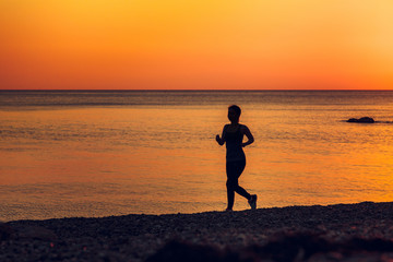 Silhouette of running women. Sea at sunset on the background