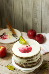 Apple cake with curd cream, decorated with painted apple on the background of autumn composition. Rustic style.